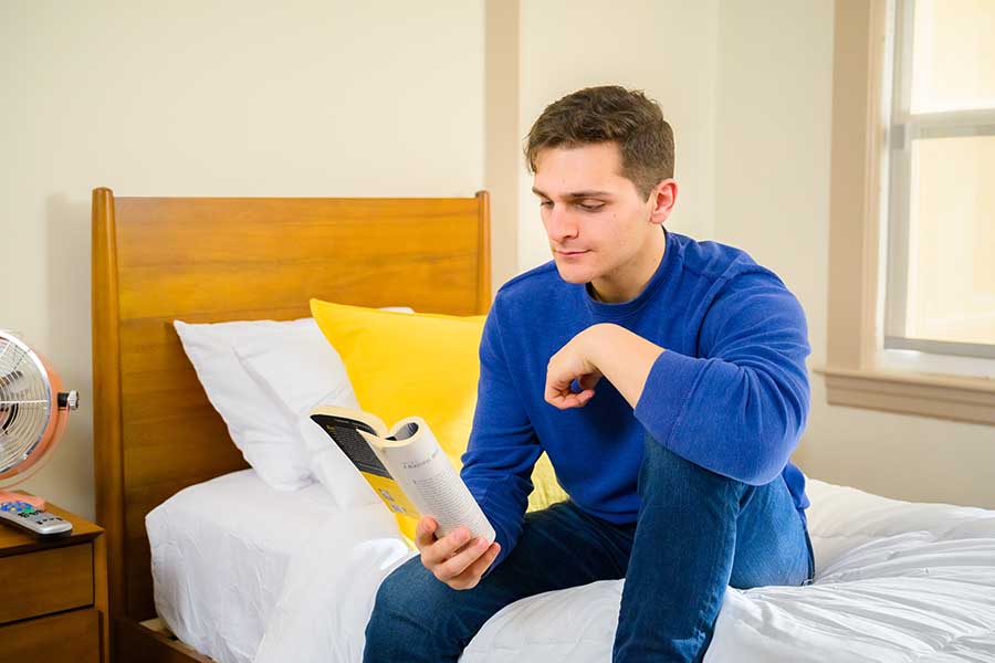 a male patient sitting on the bed reading