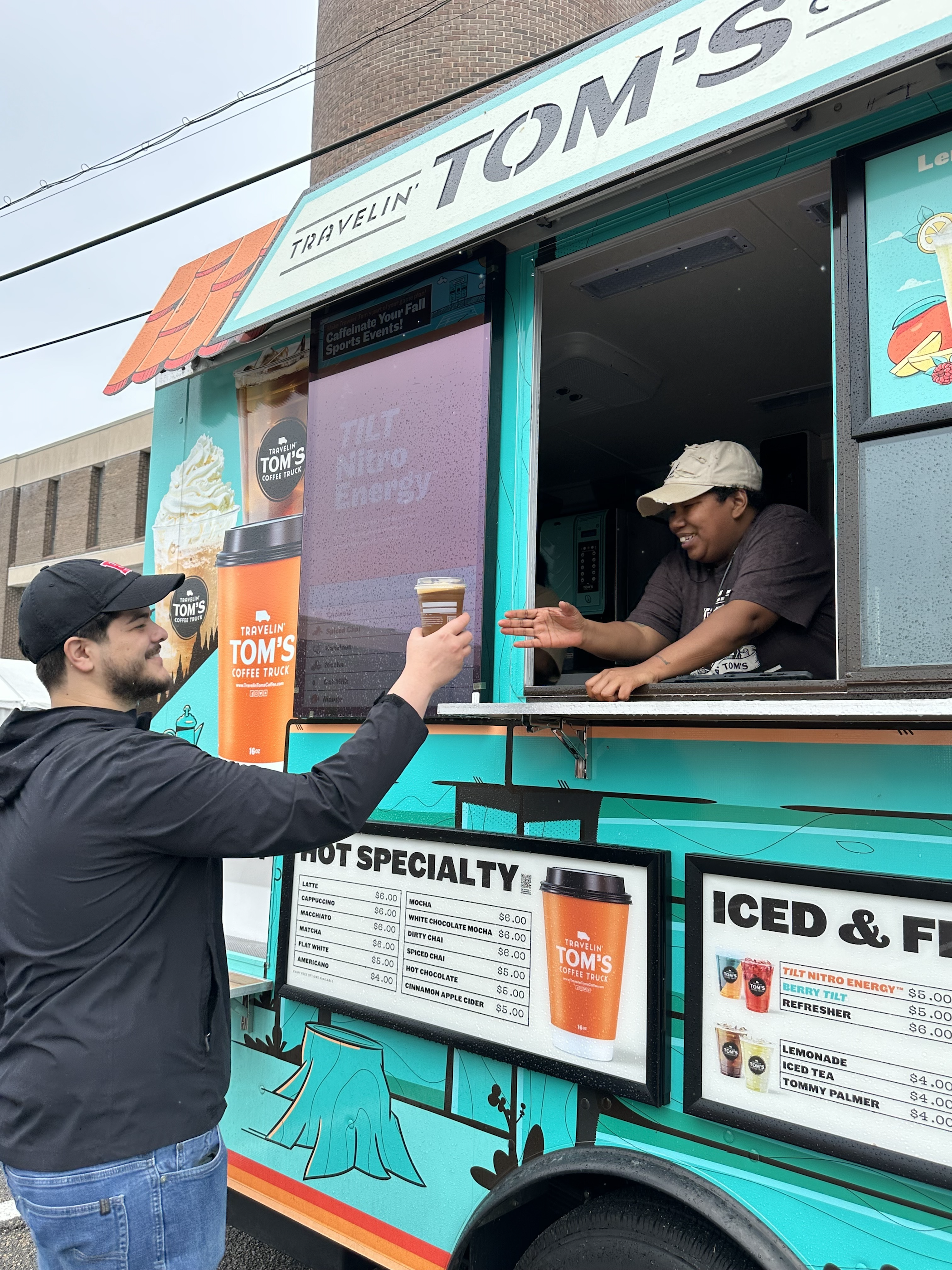 A Rutgers Day participant receiving coffee from a food vendor