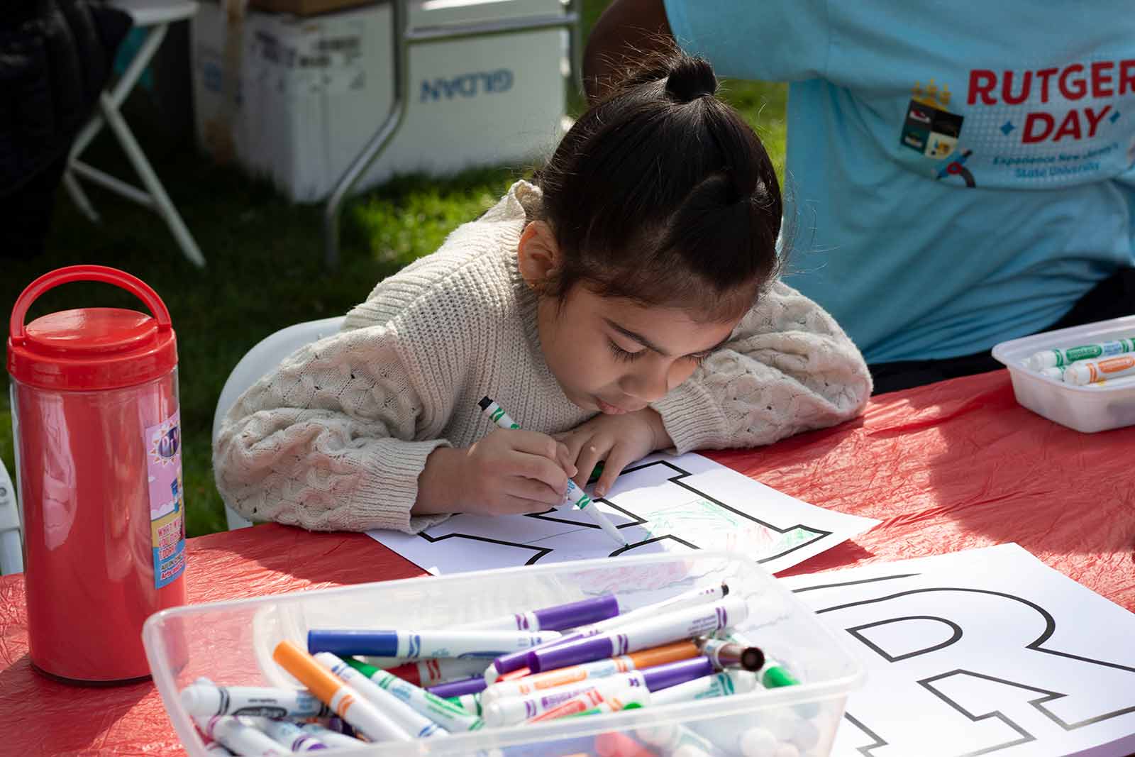 Luciana Medina colors a Rutgers “R” at the R Garden on Voorhees Mall during Rutgers Day 2024.
