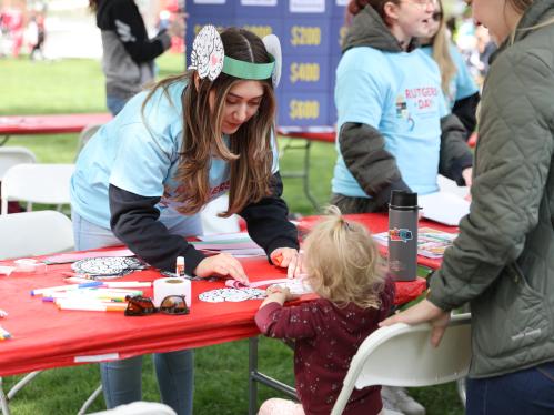 A child stops at a program table on Rutgers Day