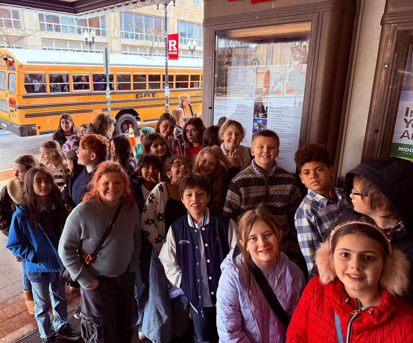 May be an image of one or more people, people standing, bus, school bus and text that says 'R - TUS EAI Ai MIDD'