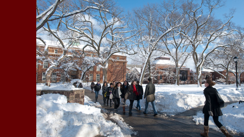 Students walk on snowy sidewalks during class change on Voorhees Mall in winter