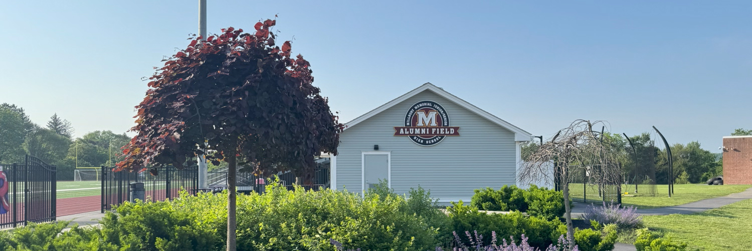 A white building with a peaked roof is seen under a clear blue sky.