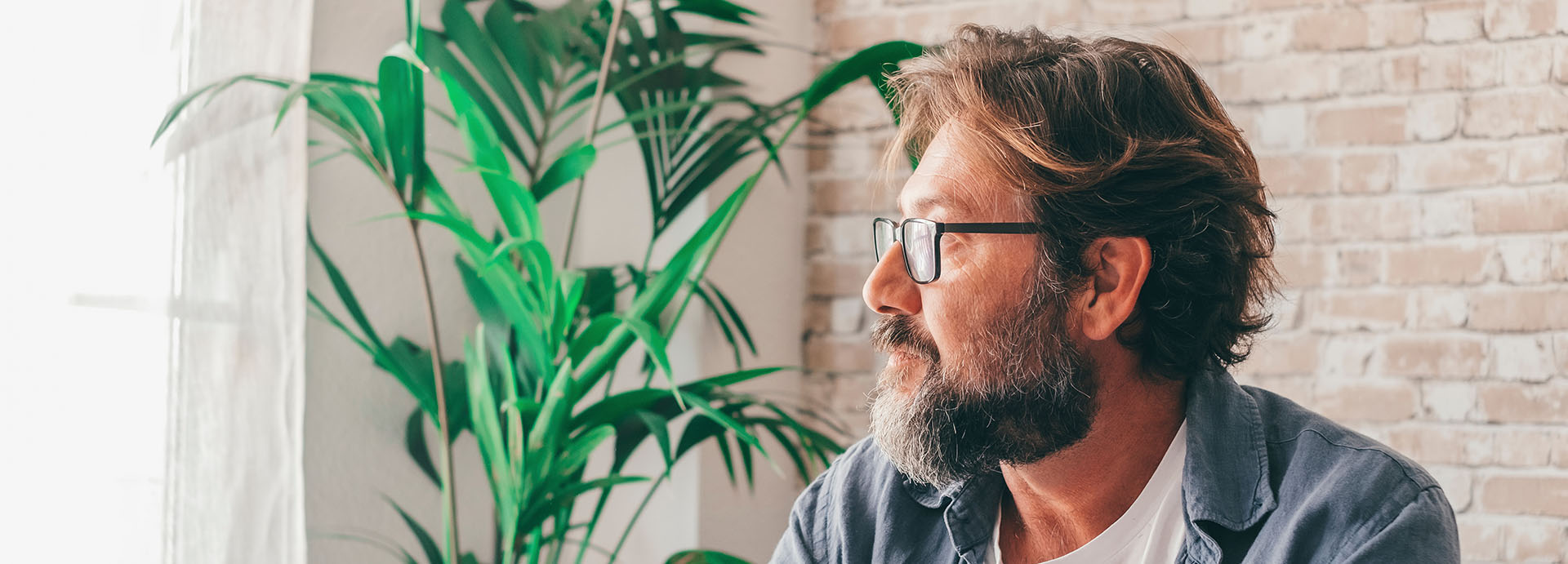 Pensive man looking out the window from a couch